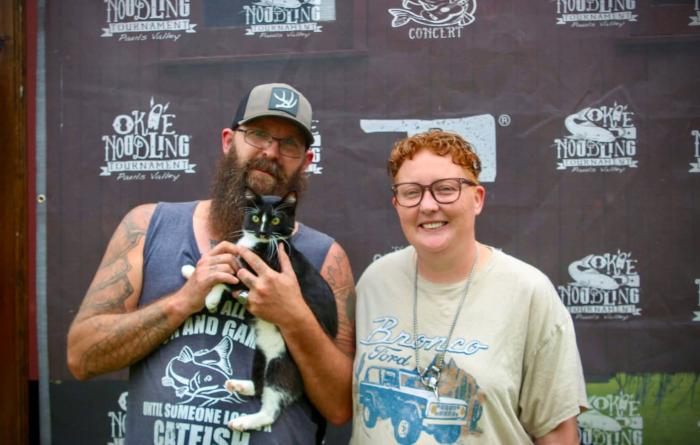Two people with a black and white cat at the Bark in the Park event