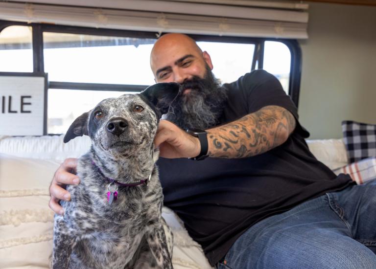 Chris Alton sitting next to a dog in their RV
