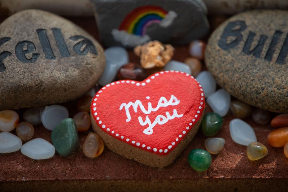 Memorial markers including a red heart-shaped stone that says, 'miss you'