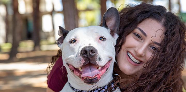 Smiling woman with her face next to a smiling dog