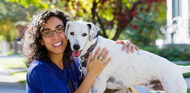 Smiling woman hugging a white dog with some black spots