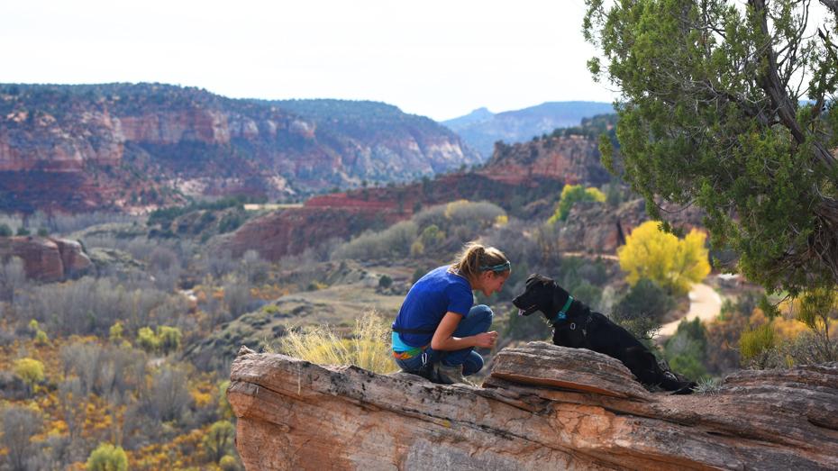 Person kneeling next to dog overlooking canyon at Best Friends Animal Sanctuary