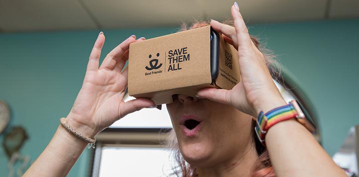 Woman holding a Best Friends branded cardboard virtual reality (VR) viewer