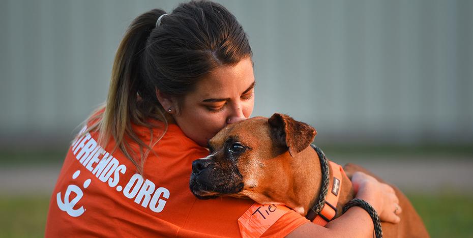 Person in a Best Friends T-shirt hugging a dog