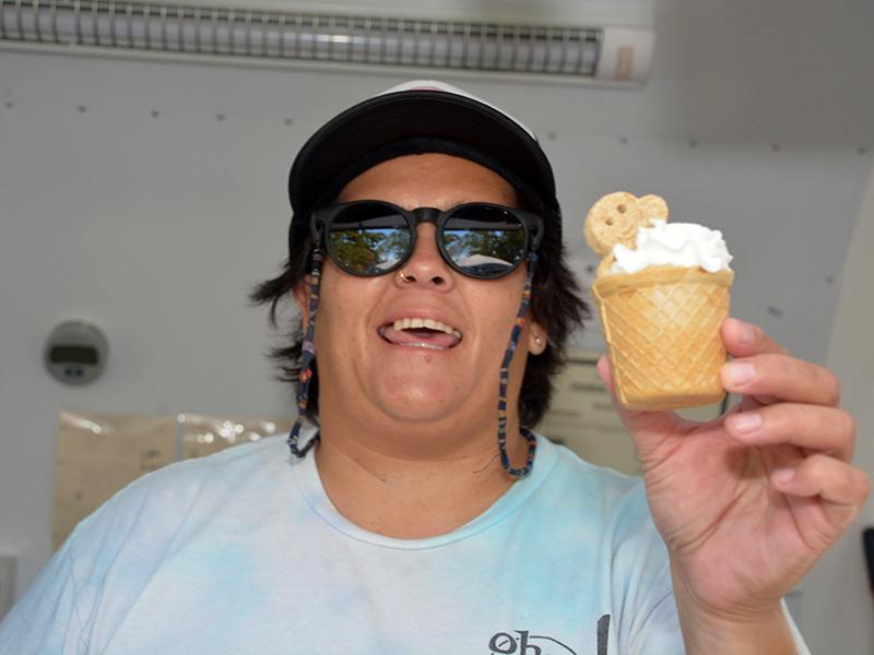 Smiling person holding an ice cream cone for a dog