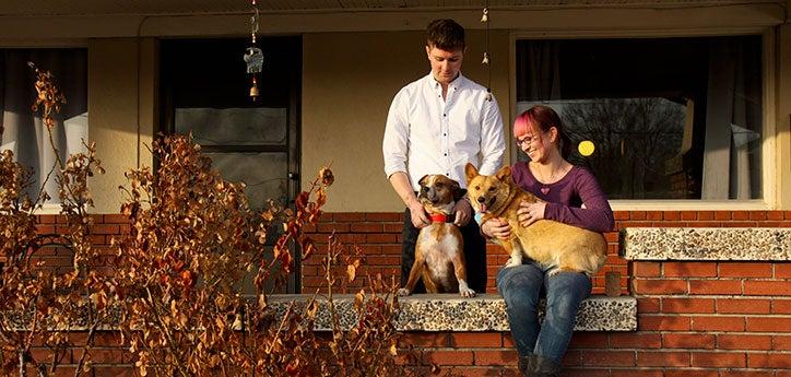 couple and two dogs in front of a pet-friendly rental house
