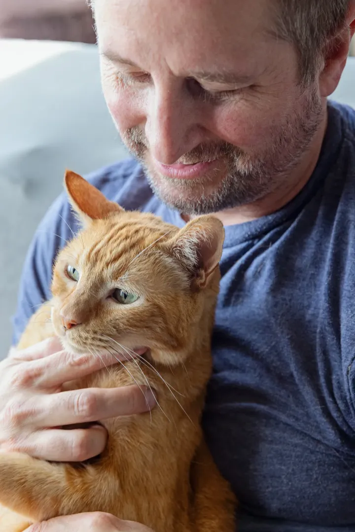 White man with an orange cat in his arms