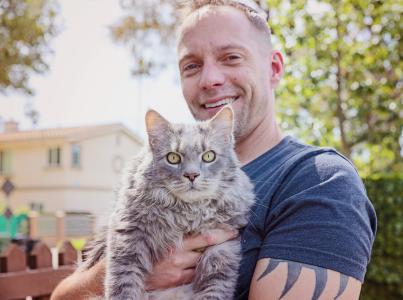 Man holding long haired gray tabby cat