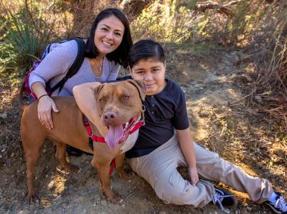 Woman and son hugging their dog on a hike.