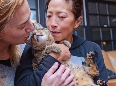 Two women kissing their newly found cat.