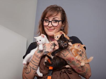 Woman holding a litter of kittens.