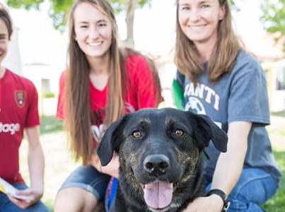 Three people and a dog smiling.