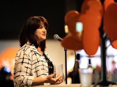 Woman speaking into a microphone at an event.
