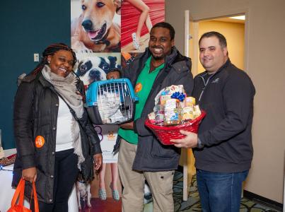 Smiling family holding cat and donations.