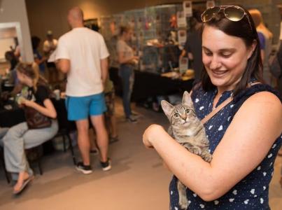 Woman holding a cat at an event.