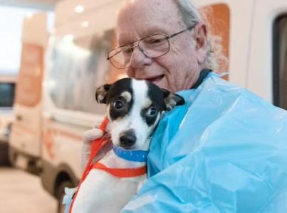 Man holding dog before transport.