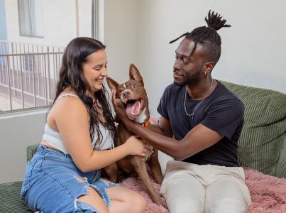 Happy family cuddling with their dog on the couch.