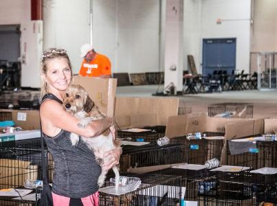 Volunteer holding a dog in front of countless crates.