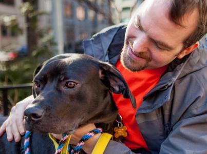 Smiling person taking a dog for a walk in New York City