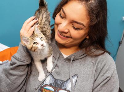 Smiling person sitting with a kitten on their shoulder