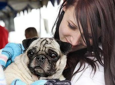 Smiling person holding a pug dog