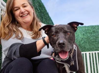 Smiling person sitting next to a dog on steps outdoors