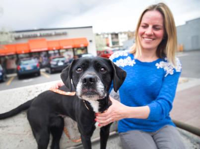 Smiling person sitting with a dog in from of Best Friends Pet Adoption Center in Salt Lake City, Utah