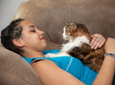 Woman on couch with cat laying on her chest