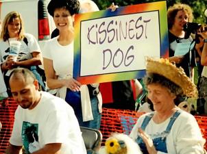Woman holding "Kissingest dog" sign in Strut Your Mutt crowd