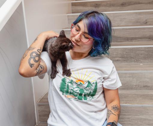 Person holding a black kitten on her shoulder