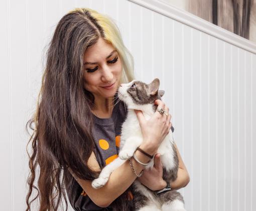 Smiling person holding a cat in her arms