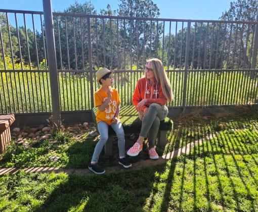 Julian Lin sitting on a bench inside a fence with Best Friends CEO Julie Castle