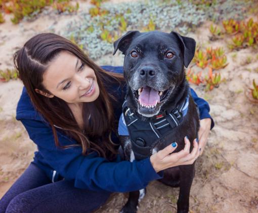 Smiling person sitting down while on a hike with a dog