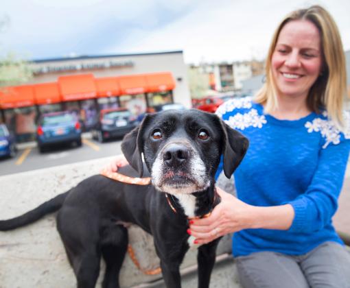 Smiling person sitting in front of Best Friends Pet Adoption Center in Salt Lake City with a dog