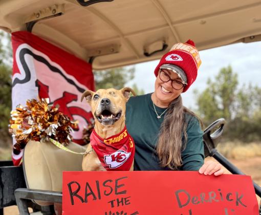 Norberta the dog wearing a Kansas City Chiefs bandanna behind a sign