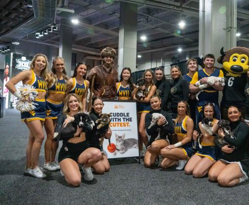 Cheerleaders holding puppies beside a Best Friends sign