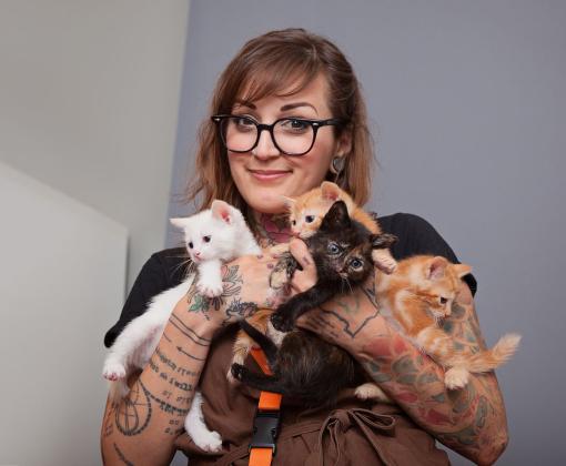 Smiling woman holding an armful of kittens