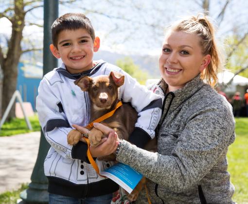 Two smiling people in a park with a tiny dog