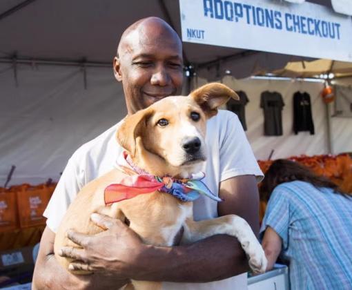 Smiling person holding a dog at a pet adoption event in Salt Lake City