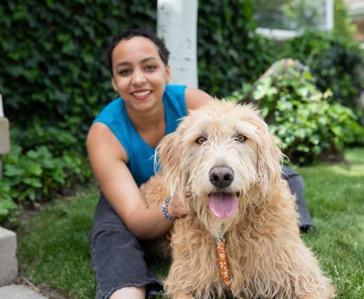 Smiling person sitting with a dog in a yard in Salt Lake City