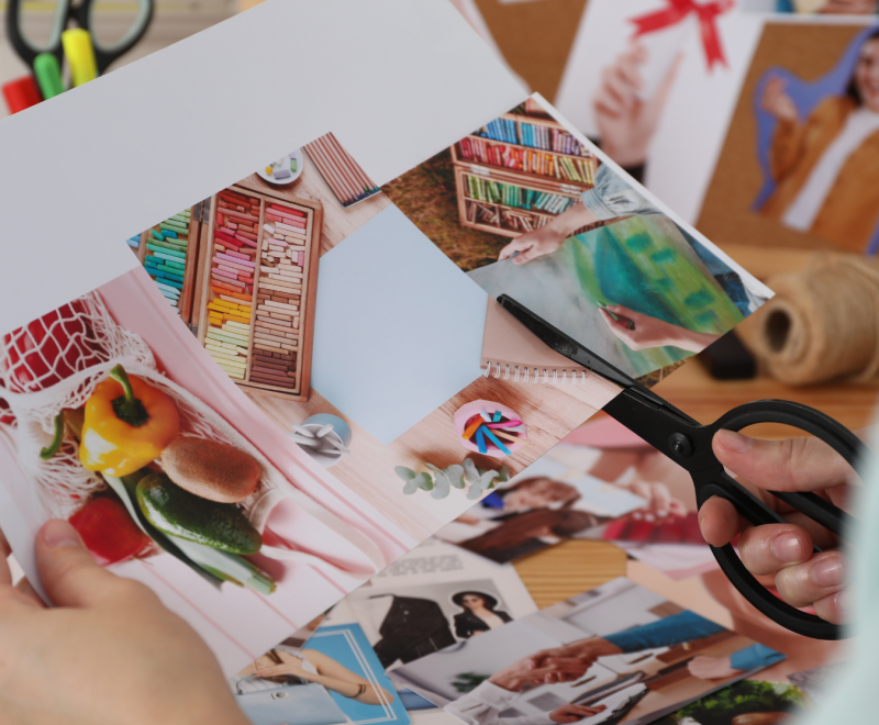 A woman's hands holding scissors and cutting out printed pictures.