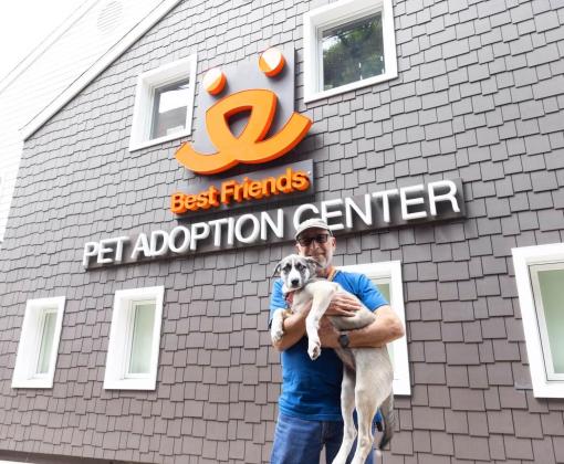 Smiling person holding a dog outside of the Best Friends Pet Adoption Center in Los Angeles