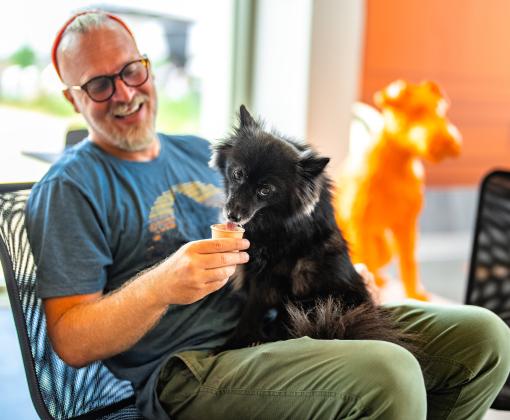 Smiling person giving a dog an ice cream cone at the Best Friends Pet Resource Center in Bentonville Arkansas