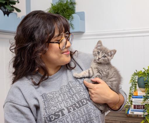 Person wearing a Best Friends sweatshirt holding a tiny kitten
