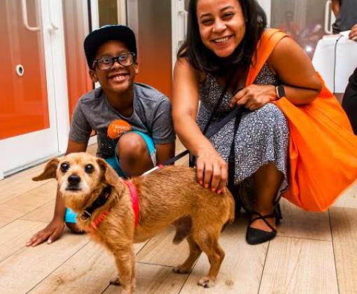 Two smiling people with a dog at Best Friends Pet Adoption Center in New York City