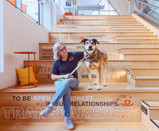 Person sitting on the steps with a dog at the Best Friends Pet Resource Center in Bentonville, Arkansas