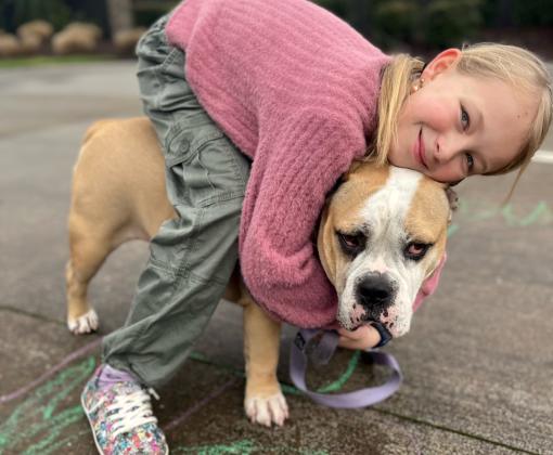 Child wearing BOBS® from Skechers® hugging a dog