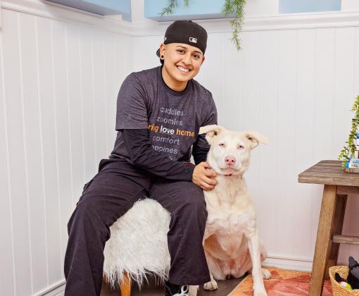 teenager sitting on chair next to large white dog in living room type setting