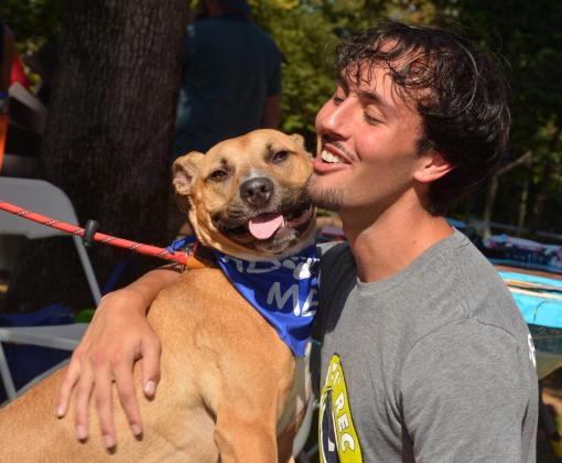 Smiling person giving a hug to Cashew the dog, who is also smiling