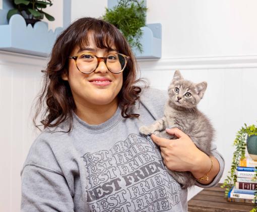 Smiling person holding a tiny kitten